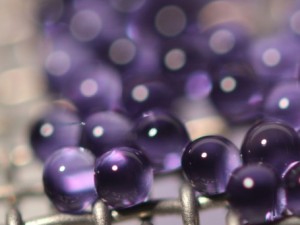 Microcapsules containing sodium carbonate solution are suspended on a mesh during carbon dioxide absorption testing. The mesh allows many capsules to be tested at one time while keeping them separated, exposing more of their surface area. Credit: John Vericella, Lawrence Livermore National Laboratory.